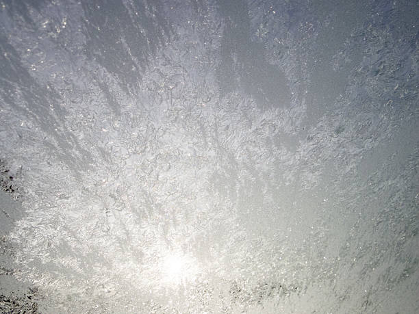 Intricate frosty patterns covering a window pane on a cold winter day