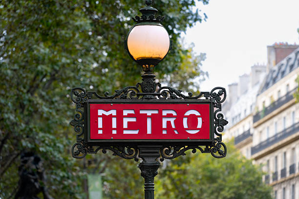 This image captures an iconic, close-up view of a historic Parisian Métro station sign.The central element is a rectangular red sign with the word \