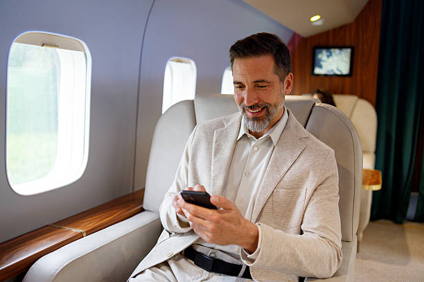 istock Man in a private jet cabin smiling, checking messages on a smartphone. He is enjoying modern connectivity while flying 2246077258