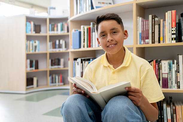 istock Happy boy reading a book at the school library 2246082286