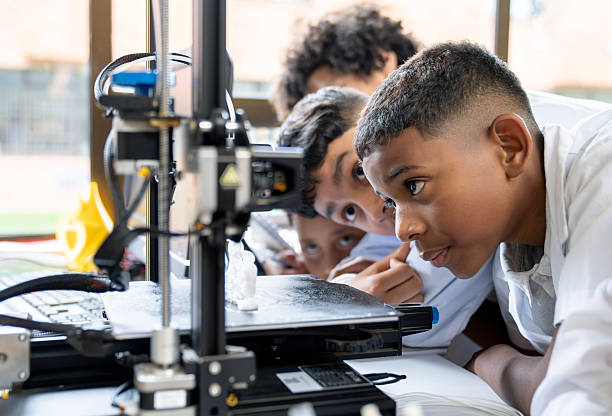 Group of young Latin American students printing a 3D object in an engineering class at the school
