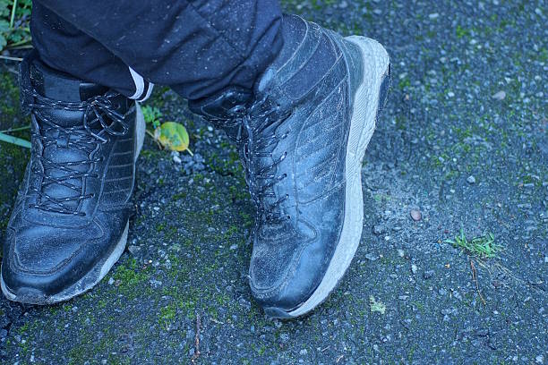 istock Two black leather sneakers on a man's feet stand on gray asphalt 2246082653
