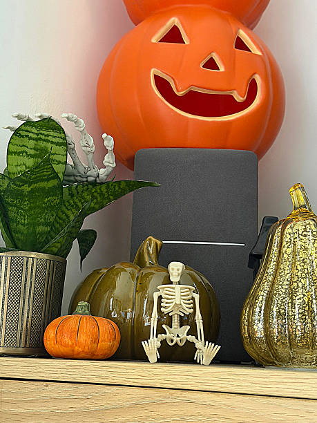 istock Close-up image Halloween decoration display arranged on wooden sideboard, stack of orange Jack O'lanterns on speaker, glazed china gourds and pumpkin, plastic skeleton, black model house, potted plants, focus on foreground 2246085804