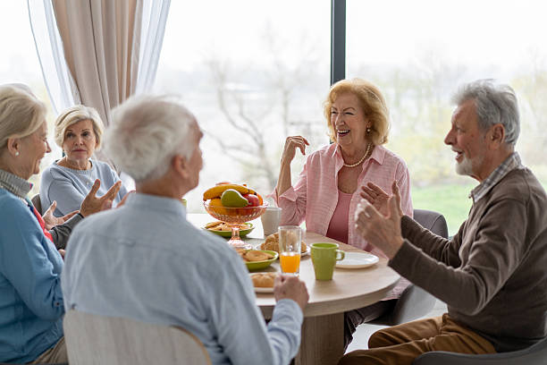 istock Senior Group Laughing Over Breakfast Table in Cozy Space 2246086927