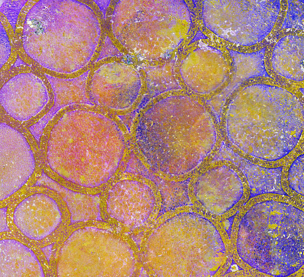 This abstract painting has prominent shades of purple, yellow and pink. There is a grunge texture throughout with large and small circles. It is painted with acrylic paint on paper.