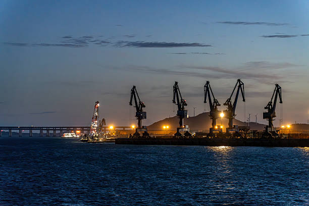 The port lights up at dusk, and cranes are at work.
