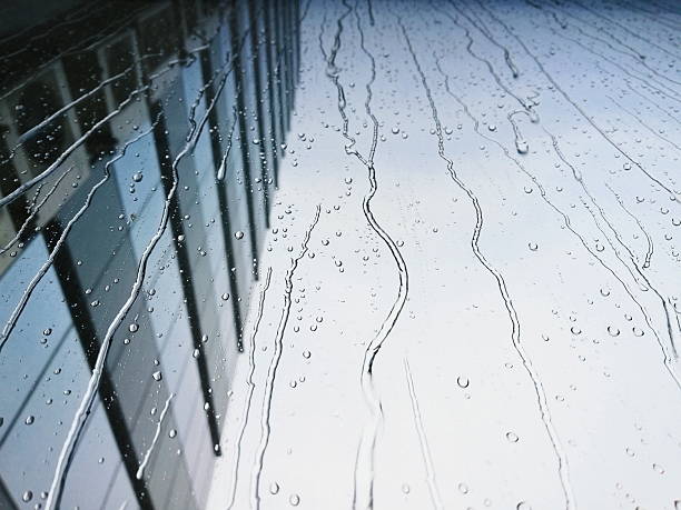 istock Rain drops on the window glass with skyscraper wall on the background 2246105990