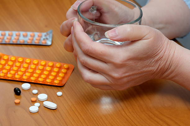 istock Patient preparing to take medication with pills arranged nearby 2246112674