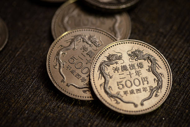 500 yen coins featuring dragons lie on rustic wooden surfaces.