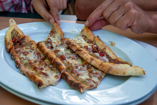 Traditional Turkish cuisine : Pita(pide) with minced meat and cheese, close up.The woman and a man is eating the pita.