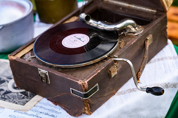 Old gramophone with hand-crank mechanism and metal horn, set on a textured table. A nostalgic glimpse into early 20th-century sound technology.