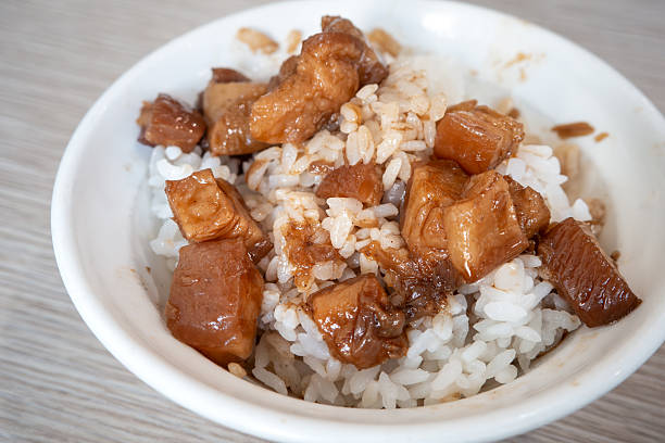 Braised pork belly meat rice, stewed pork over cooked rice in a white bowl with a metal spoon