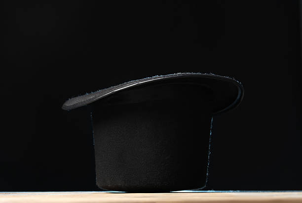 istock Magician's hat on wooden table against black background 2246120381