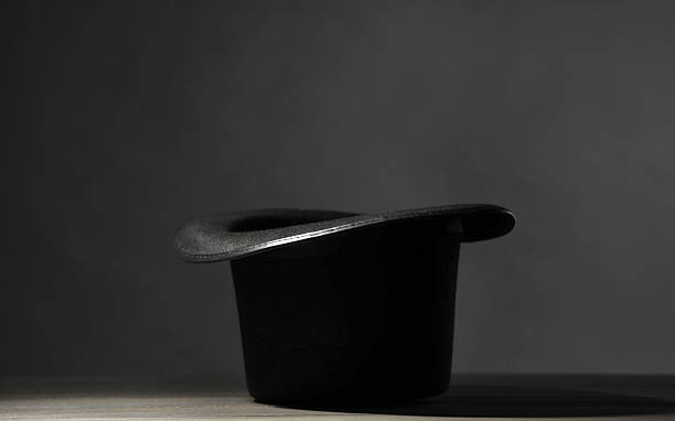 istock Magician's hat on white wooden table against black background 2246120444