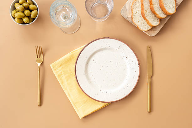 istock Festive table setting with empty plate, cutlery and napkin - bread and olives for dinner, flat lay. Top view 2246121255