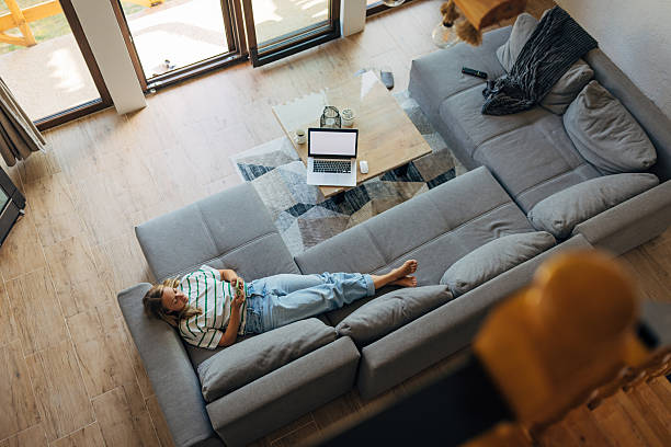 istock High angle view of woman lying barefoot on sofa and relaxing from remote work using smartphone 2246125648