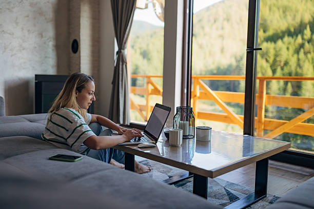 istock Female freelancer using laptop while sitting on living room floor at coffee table 2246126186