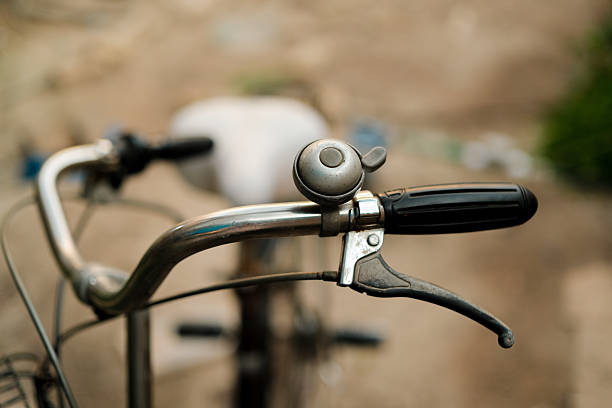 Close-up of a bicycle handlebar with a bell and brake lever, blurred background