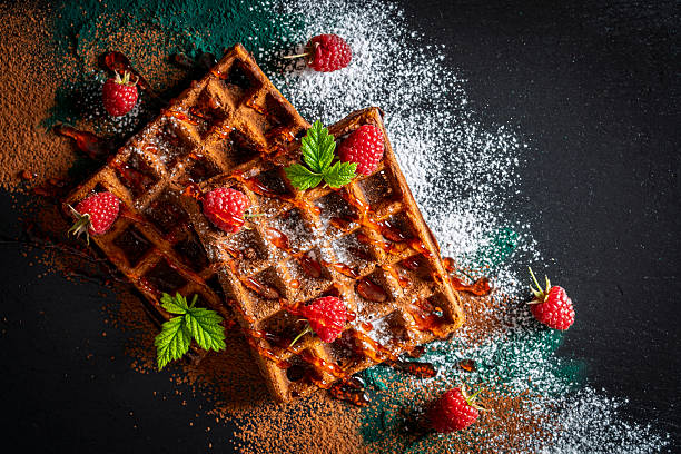 istock Fresh baked chocolate Belgian waffles with red raspberries and jam on black plate for breakfast, closeup, top view. Culinary, cooking, bakery concept. Food recipe background. Sweet waffles with berry 2246129428