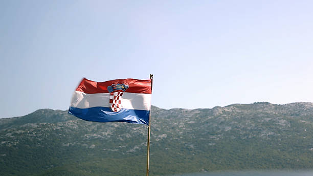 Croatian flag blows in wind, hills distant