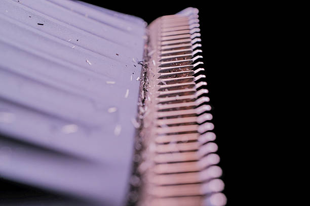 Close-up of a comb with fine teeth, showing hair strands and debris, against a dark background