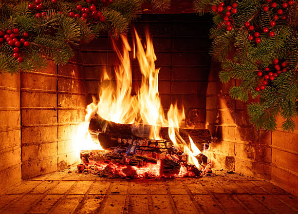 Warm Christmas fireplace featuring glowing festive garland and burning logs creating the cozy holiday mood indoors stock photo