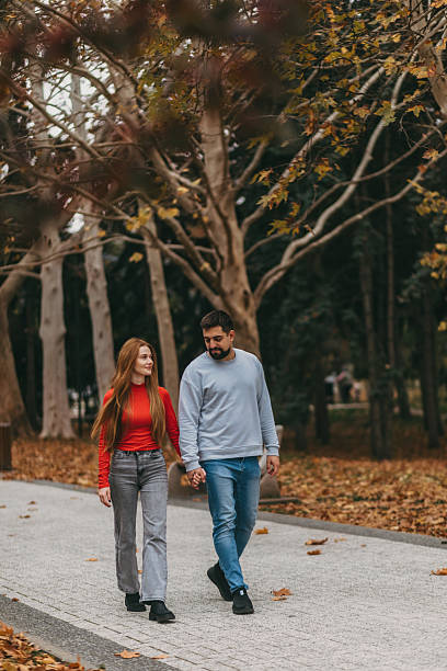 istock Two people sharing leisurely walk amid autumn leaves under warm sunlight 2246132097
