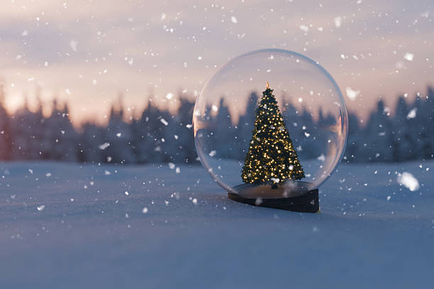 istock snow globe containing a Christmas tree with glowing lights, set in a snowy winter landscape with a blurred forest background at dusk or dawn. Falling snowflakes. Festive holidays scene. 2246133590