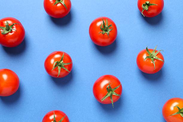 istock Fresh cherry tomatoes on blue background. Ripe vegetables 2246134642
