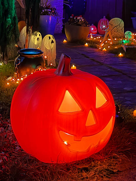 istock Image of front garden halloween decorations, plastic jack-o’-lantern pumpkin faces, scary skeletons, ghosts, pumpkins, purple, green fairy lights, creepy monsters 2246136200
