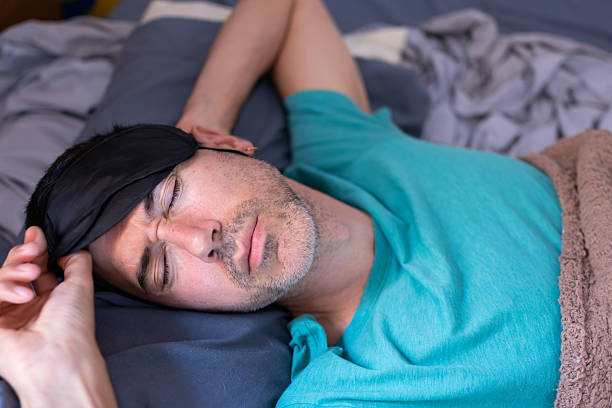 Photo of sleepy young man wake up early time lying comfortable bed want sleep white room interior inside.