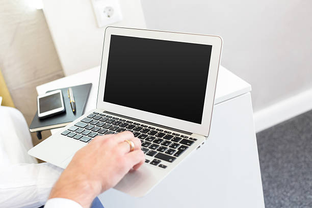 Individual is typing on a laptop while seated at a tidy desk in a well-lit room.