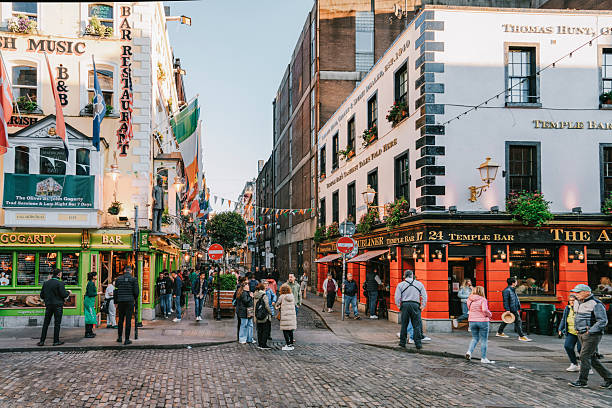 Dublin's Temple Bar district, bustling with people outside colorful pubs and restaurants during sunset, Ireland