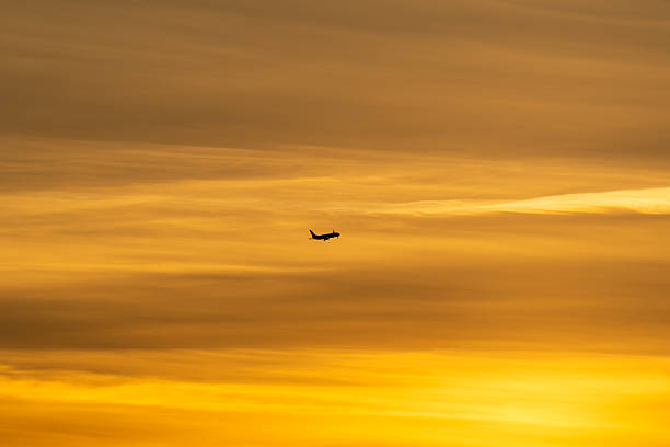 istock Passenger airplane silhouette in flight against a dramatic golden and orange sky during a beautiful sunset. 2246141875