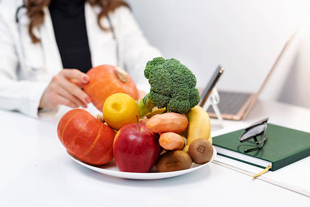 istock Close up vegetables on table. Doctor dietitian communicates with patient remotely via laptop, online consultation. Healthcare consulting. Telemedicine 2246144512