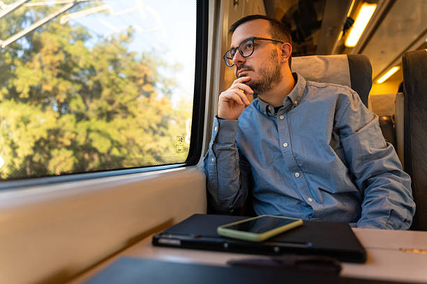 istock Man traveling by train looking out window thinking 2246144713