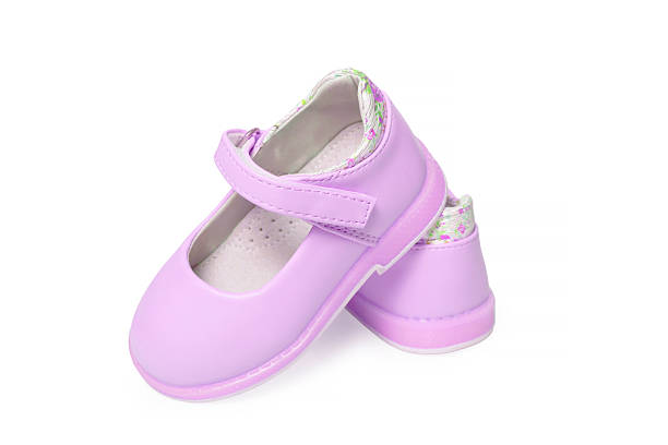 A pair of small children's pink slippers and a flower lying on them. An example of children's shoes and decorations in everyday life. Top view
