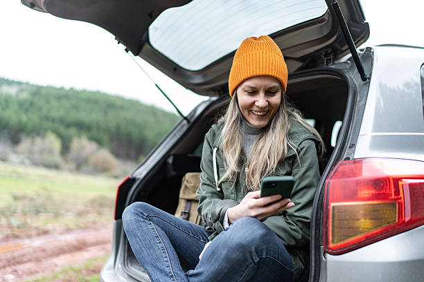 istock Woman relaxing in car trunk using smartphone 2246148230