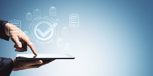istock Businessman using tablet with digital checklists and approval icons on light blue abstract background for digital quality assurance concept. 2246148759