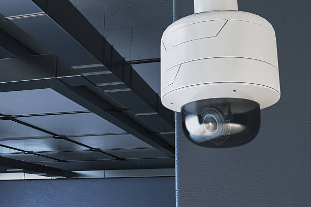 istock Modern surveillance camera mounted on ceiling corner in industrial interior with futuristic lighting and dark background. 3D Rendering. 3D Rendering 2246150096