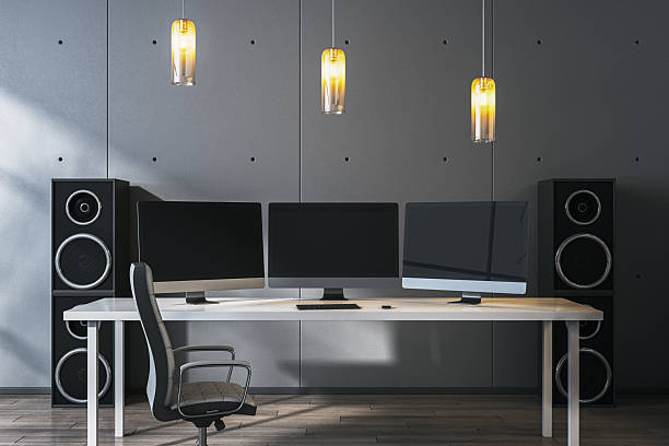 istock Modern desktop setup with triple monitors and speakers in stylish office interior under warm pendant lighting on gray textured background wall. 3D Rendering 2246150110