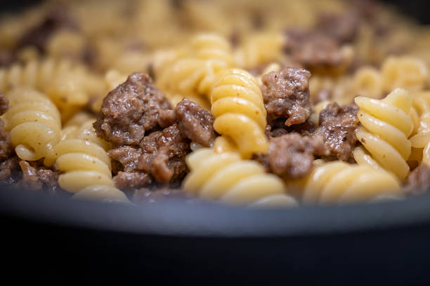 Appetizing close-up of a hearty fusilli pasta dish with savory minced beef in a pan. The shallow depth of field creates a perfect background for recipe blogs and culinary content.