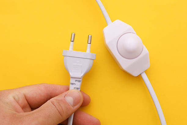 istock Male hand holding electric plug with dimmer on yellow background 2246153094