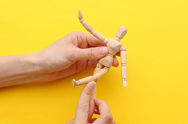 istock Hands holding wooden puppet on yellow background 2246153710