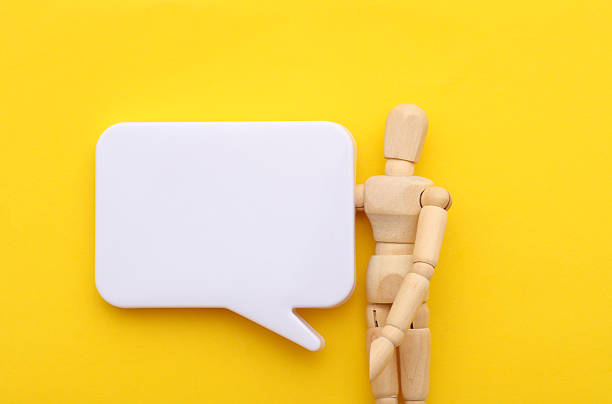 istock Wooden puppet with blank speech bubble on yellow background 2246153726