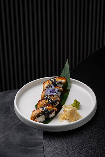 Nigiri with eel on a white plate on a black background isolated for menu