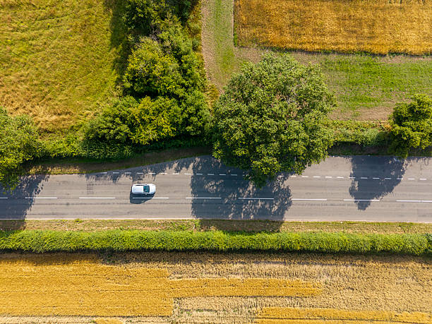 istock Rural road between farm fields with car, England 2246155715