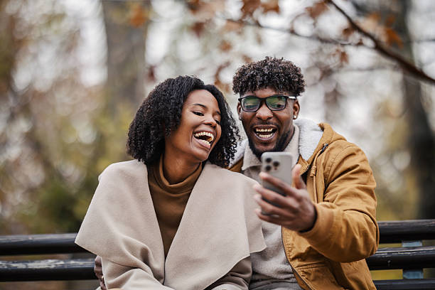 istock Happy black couple laughing watching smartphone in park 2246155881