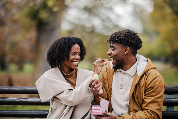 istock Young black couple sharing macarons on a park bench 2246155889