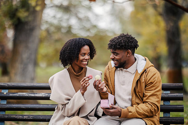 istock Happy black couple sharing macarons on park bench 2246155898